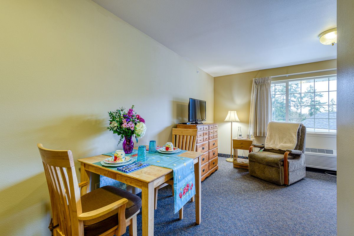 A cozy living room with a dining table set, TV, and comfortable seating by the window.