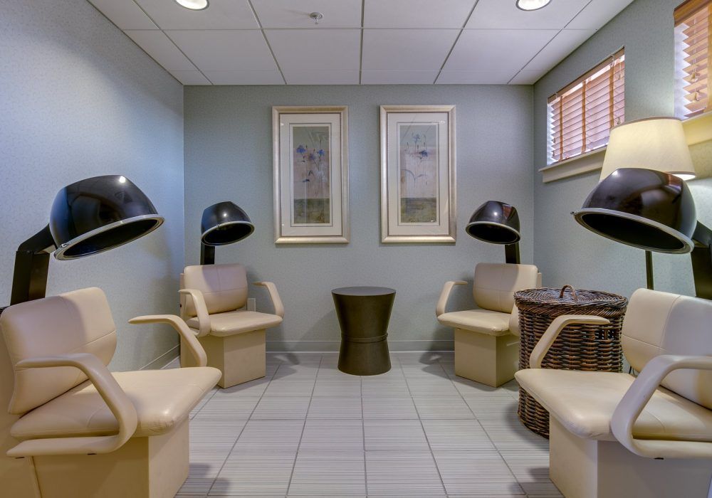 A cozy salon interior with chairs and hair dryers, accompanied by decorative wall art.