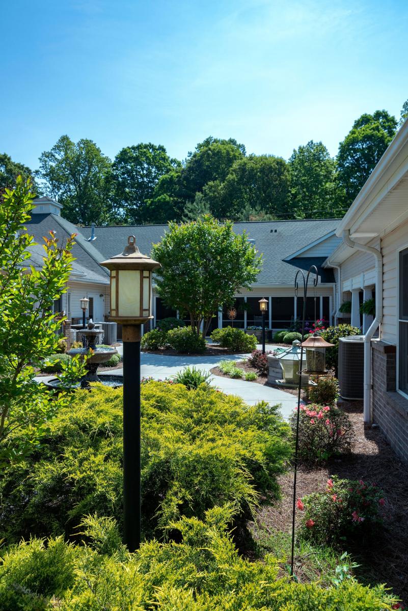 A beautifully landscaped outdoor area with lush greenery and a well-maintained pathway surrounded by buildings.
