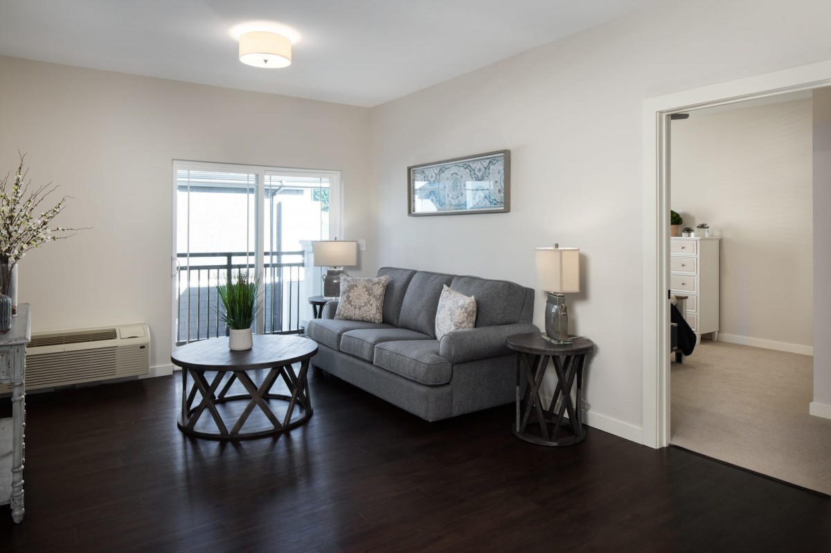 A modern living room with a cozy sofa and stylish coffee table, featuring hardwood floors and elegant lighting.