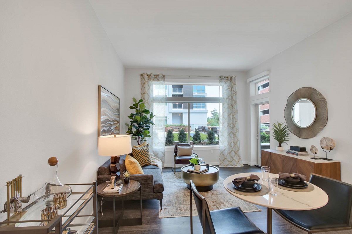 A modern living room featuring stylish furniture, large windows, and indoor plants creating a cozy atmosphere.