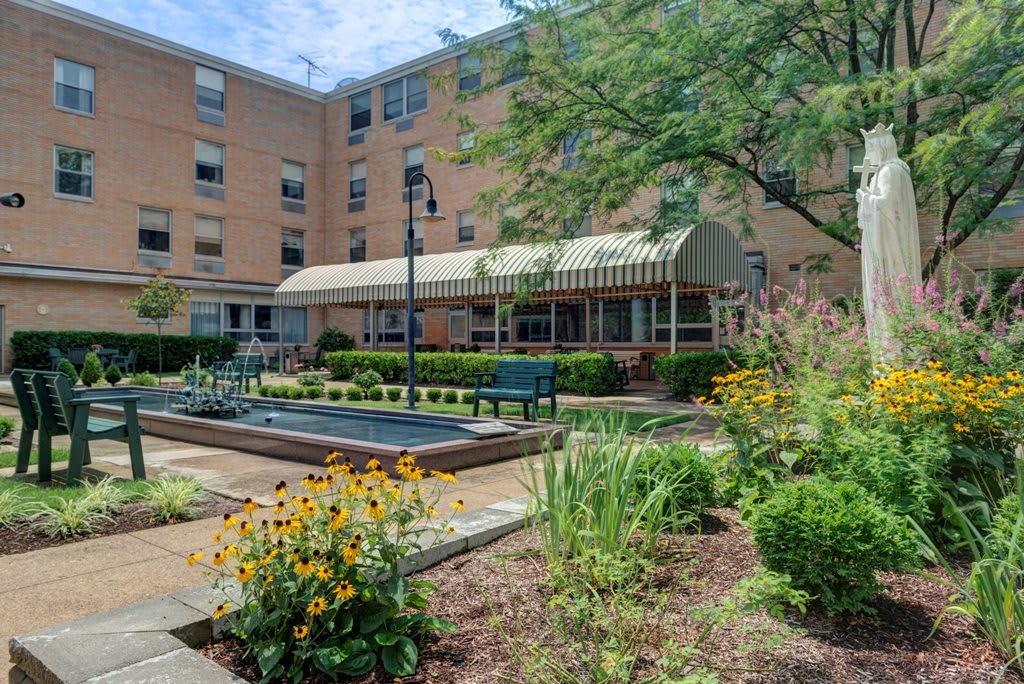 A courtyard with a garden and benches in front of a residential building.