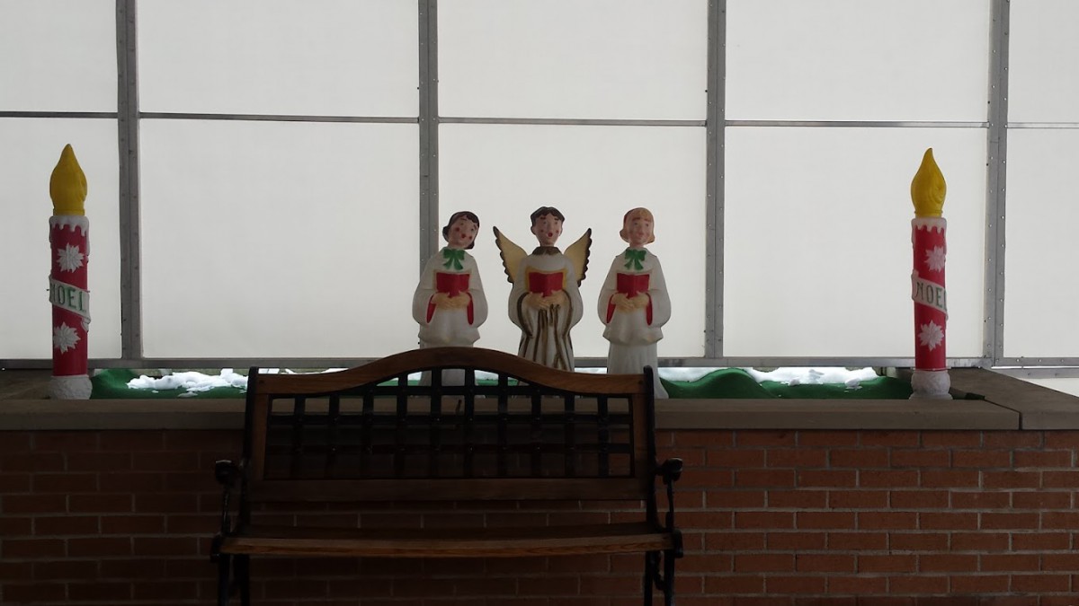 Three choir angel figurines displayed on a bench indoors.