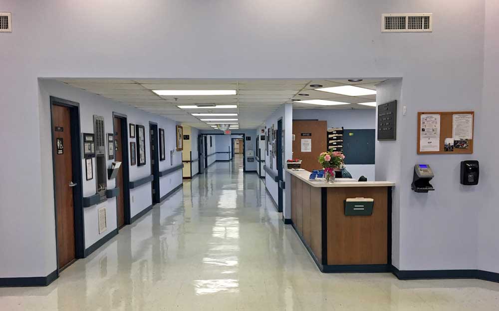 A hospital hallway featuring a reception desk and clean, bright interiors.