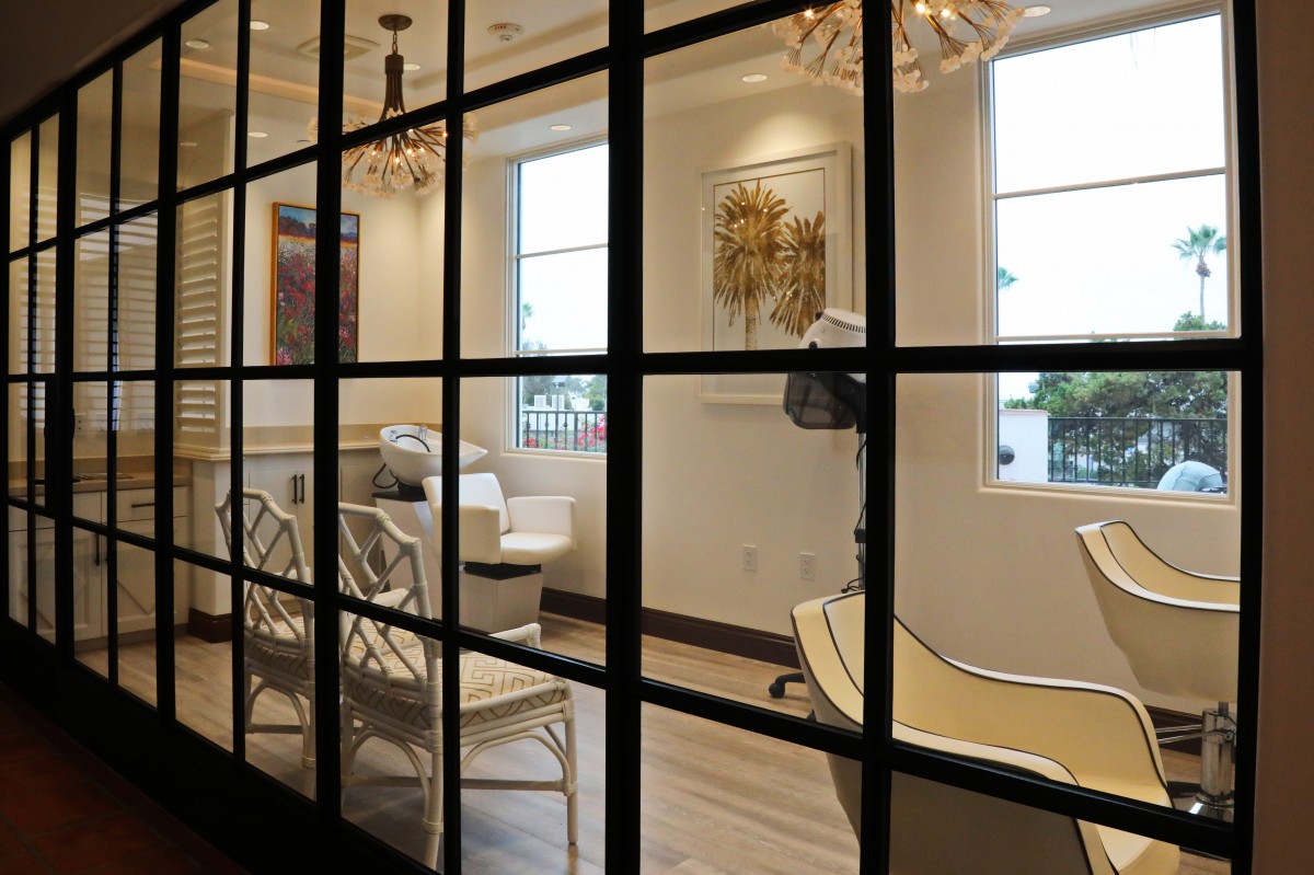 A modern salon interior with comfortable chairs and elegant chandeliers.