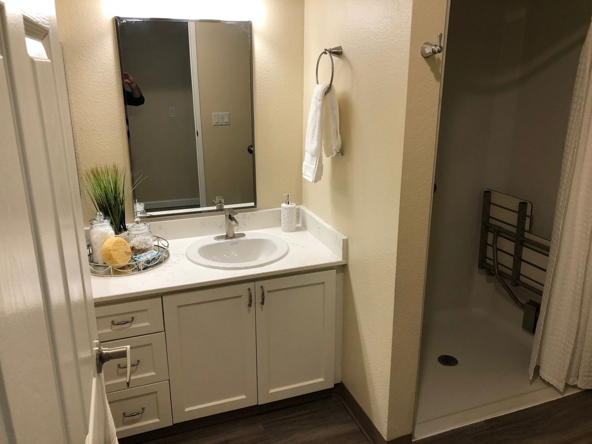 A clean and modern bathroom with a mirror above the sink and a walk-in shower.