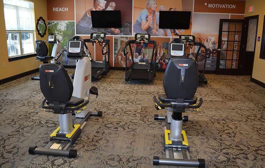 A gym with various exercise machines including treadmills and stationary bikes.