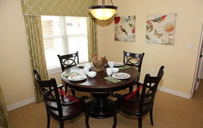 A cozy dining area with a round table set for a meal, surrounded by chairs and decorated with wall art.