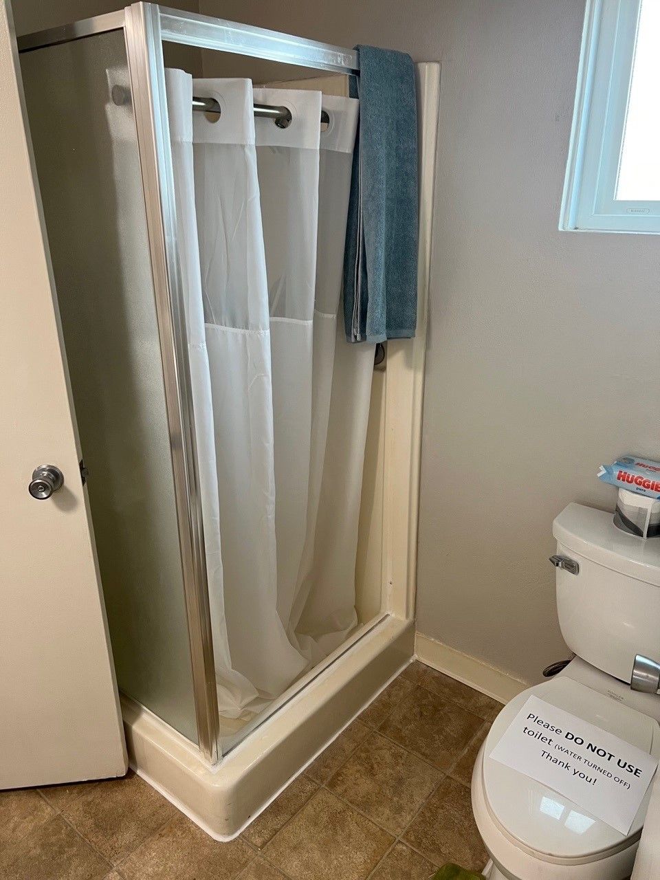 A bathroom with a shower, toilet, and towel.