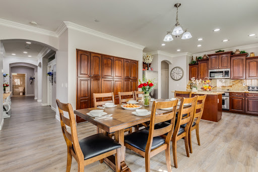 A cozy dining area with a wooden table surrounded by chairs, complemented by modern lighting and elegant cabinetry.