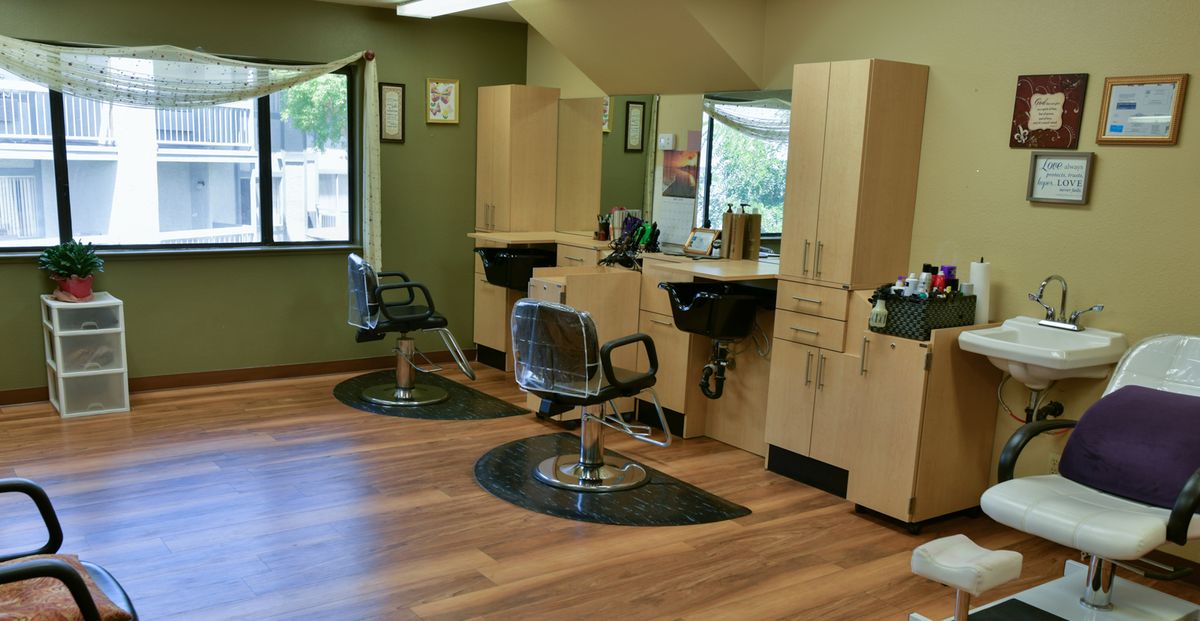 A modern hair salon with styling stations and empty chairs.