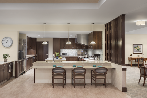 A modern kitchen featuring sleek wooden cabinetry, a spacious countertop, and stylish bar stools complemented by pendant lighting.
