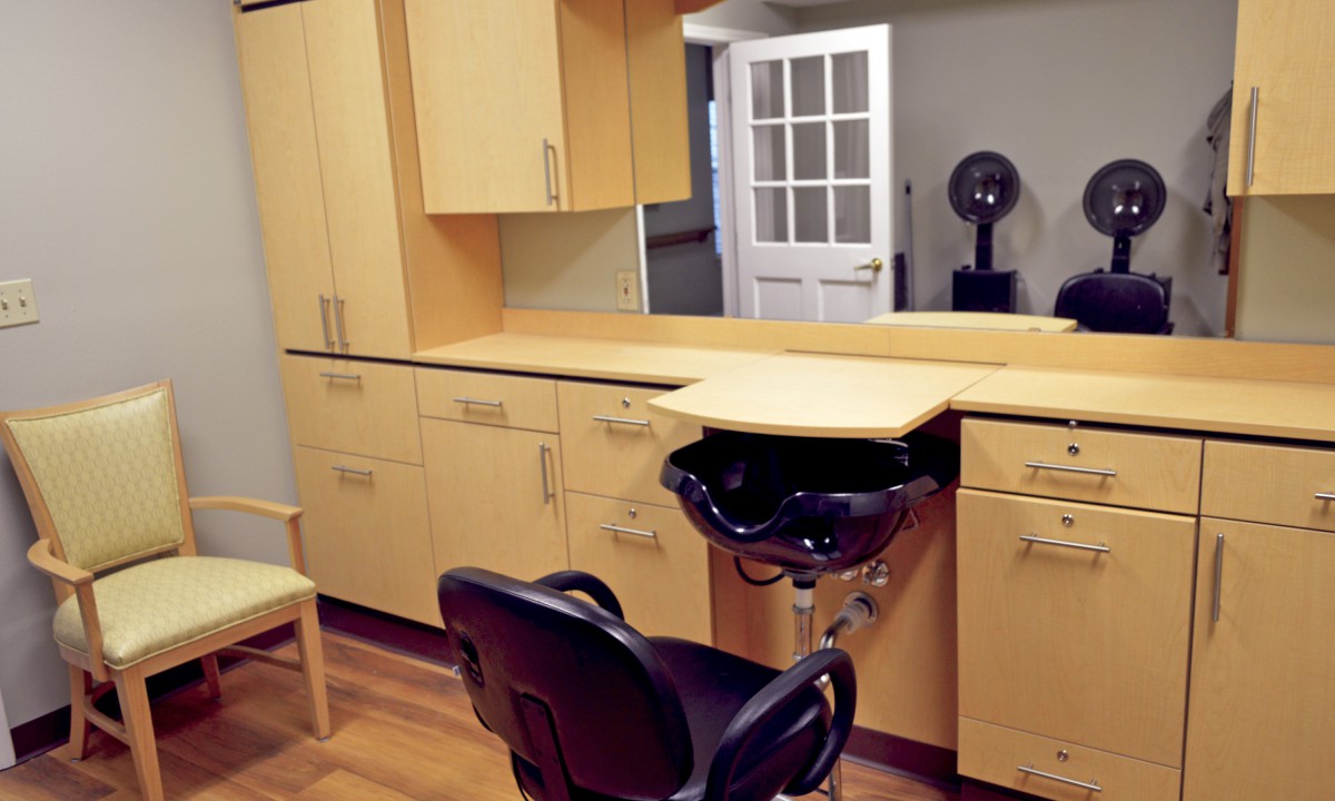 A hairdressing station complete with a sink, chair, and storage cabinets.