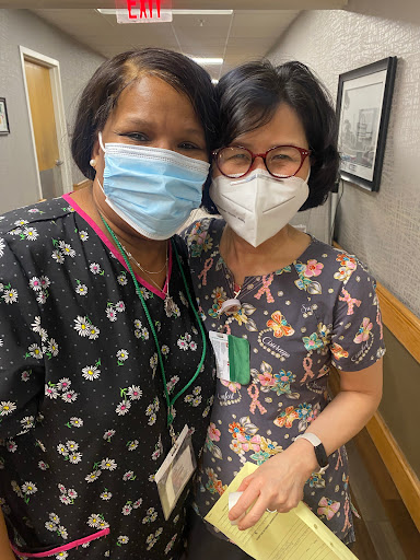 Two healthcare professionals posing for a cheerful photo while wearing masks.