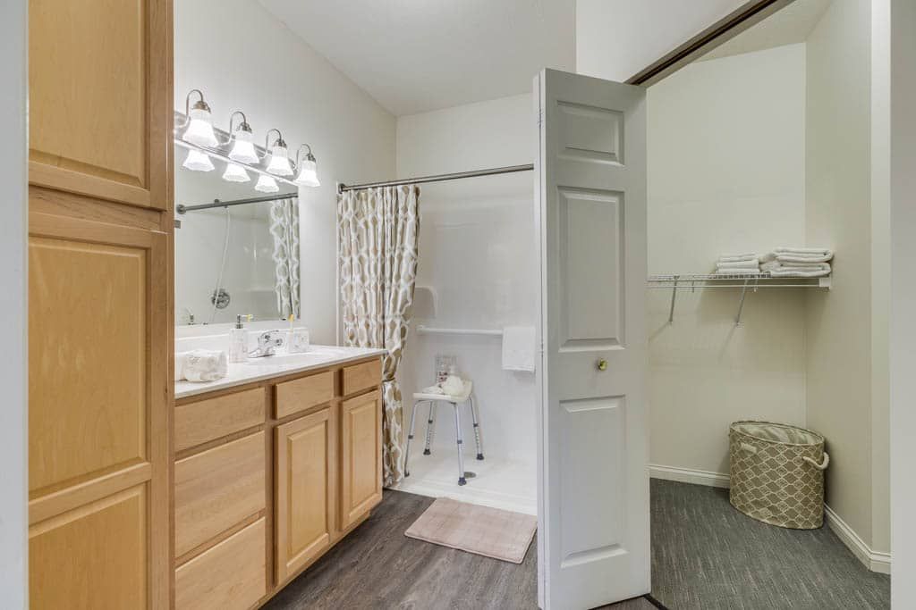 A modern bathroom with a shower, vanity, and wooden cabinets.