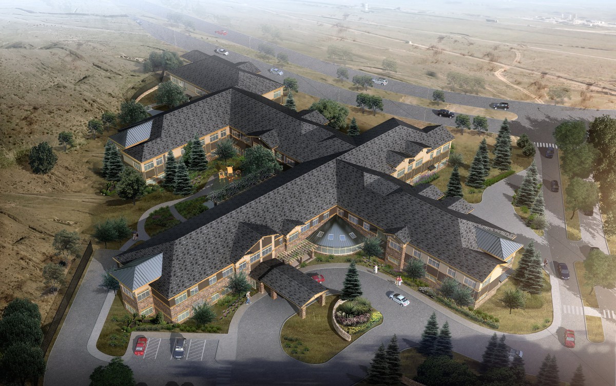 Aerial view of a large building complex surrounded by trees and roads in a scenic landscape.