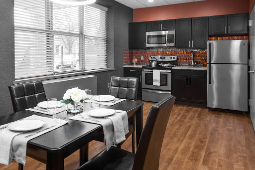 A stylish modern kitchen and dining area featuring sleek black cabinetry, stainless steel appliances, and a meticulously set dining table.