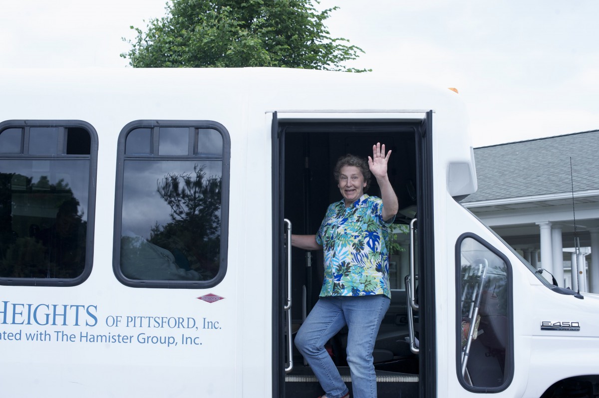 A person waving from the doorway of a bus.