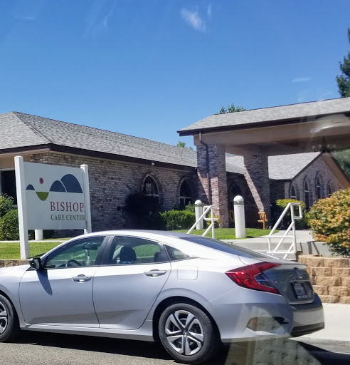 A silver car parked in front of a building with a sign.