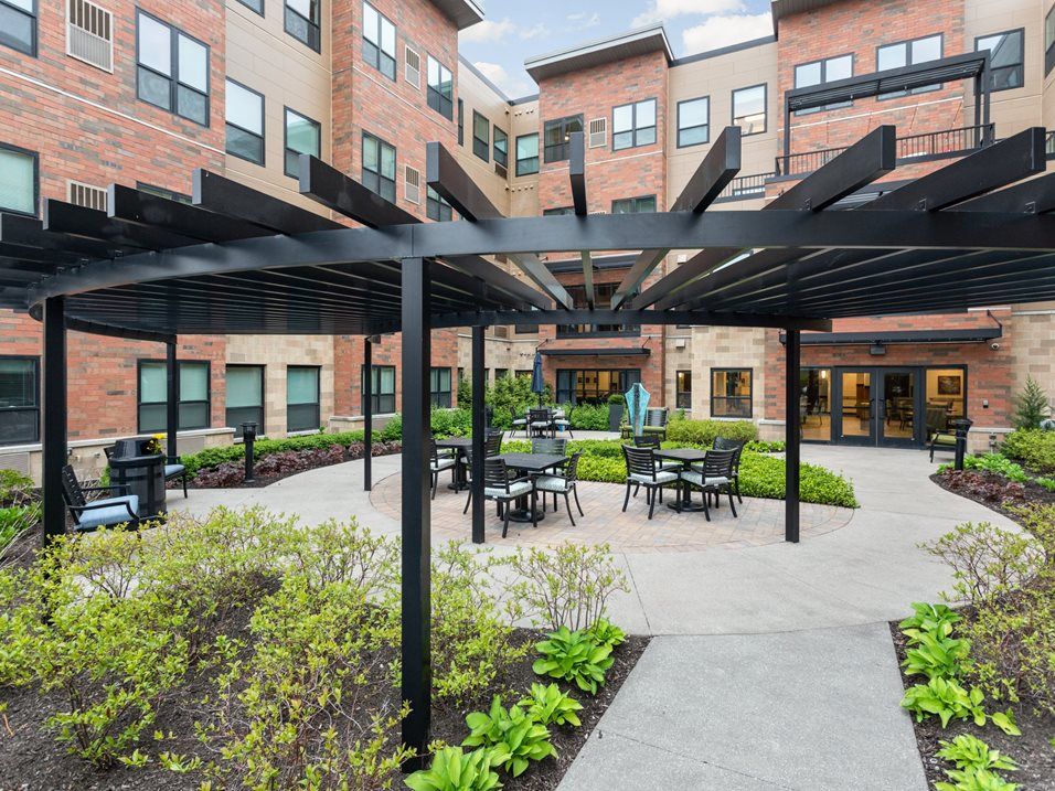 A modern courtyard with a pergola and outdoor seating in an apartment complex.