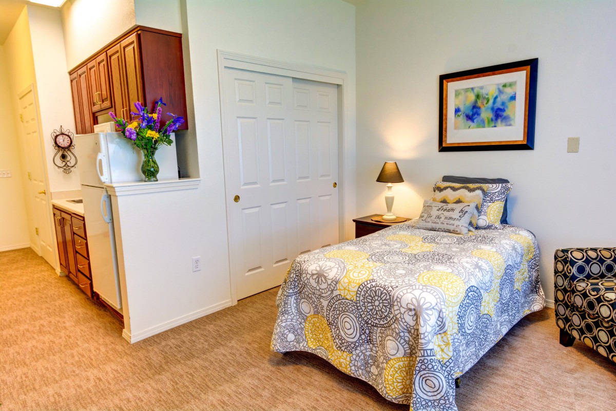 A cozy bedroom with a single bed, decorated with colorful bedding and artwork.
