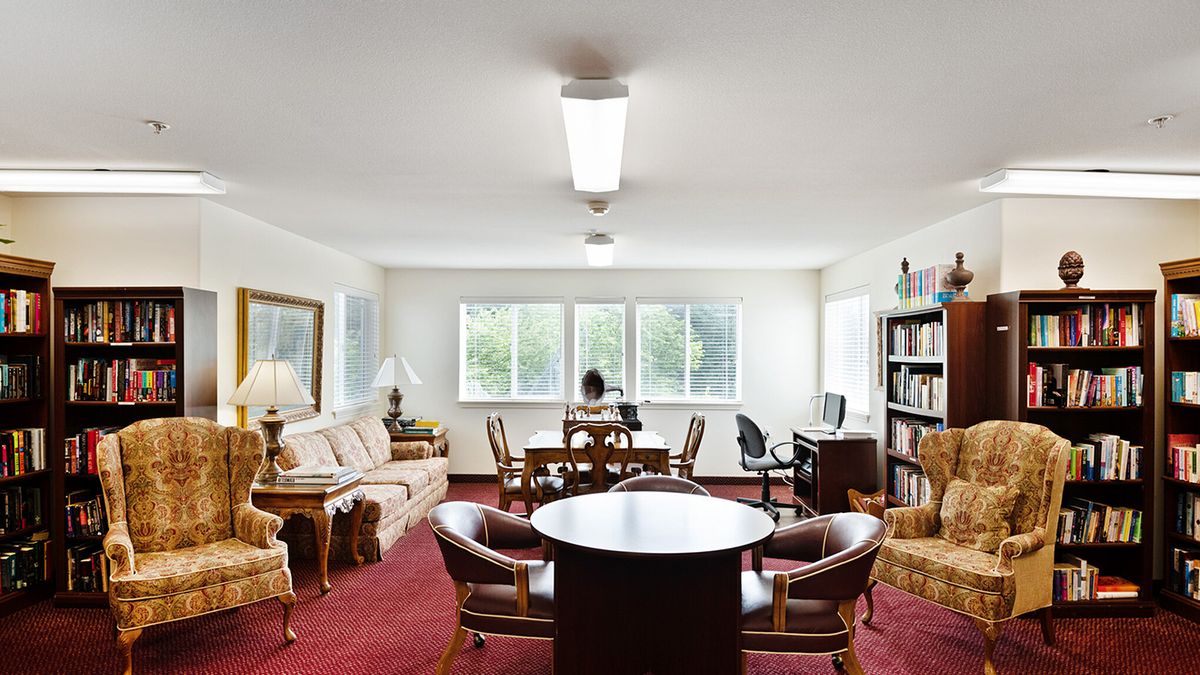 A well-lit office space with multiple seating areas, including a conference table, desk, and bookshelves.