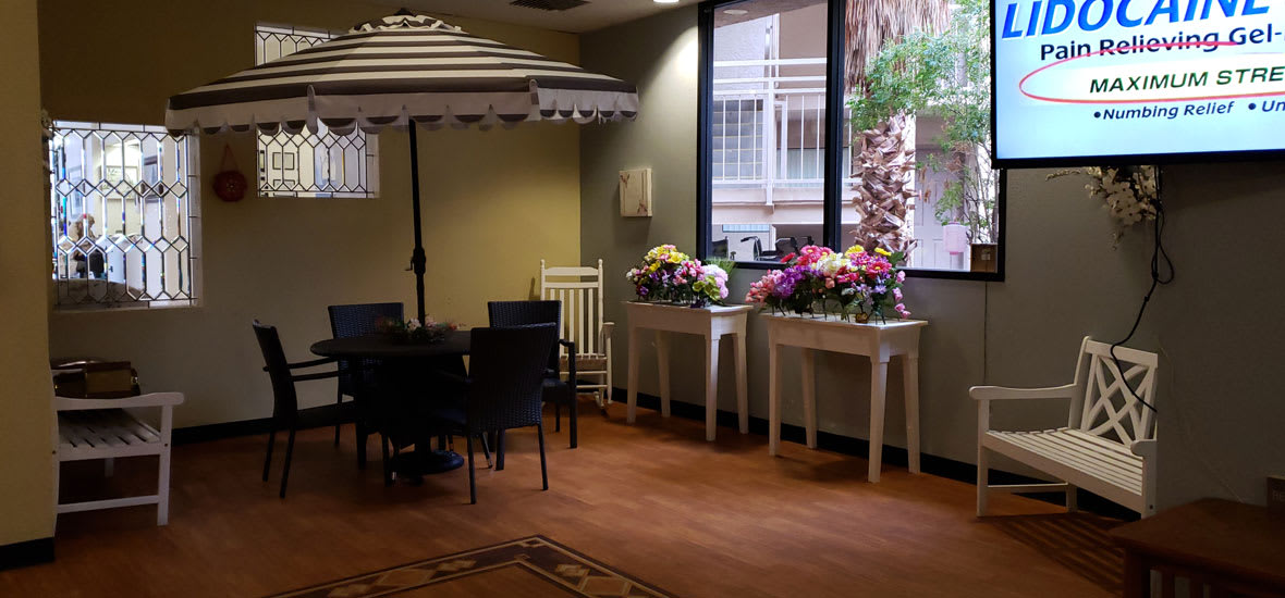 A cozy interior space with tables adorned with vibrant flower arrangements and seating under an indoor umbrella.