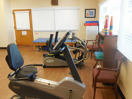 A well-equipped rehabilitation area featuring exercise machines and a comfortable seating arrangement.