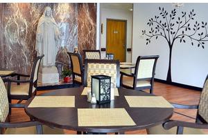 An indoor dining area with tables and chairs, featuring a statue and decorative wall art.