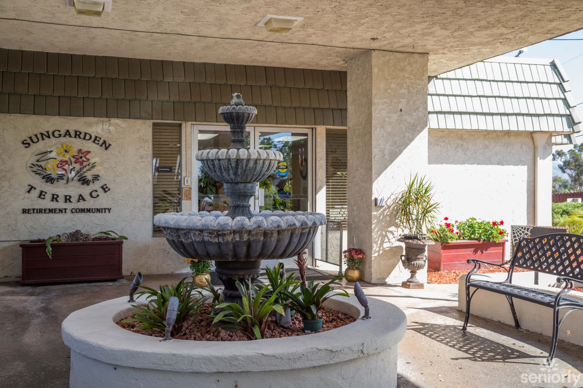 A tiered fountain surrounded by plants in a courtyard setting.
