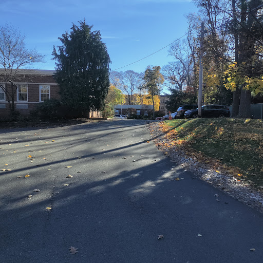 A peaceful residential street in autumn, featuring a yellow truck parked near the house and colorful foliage.