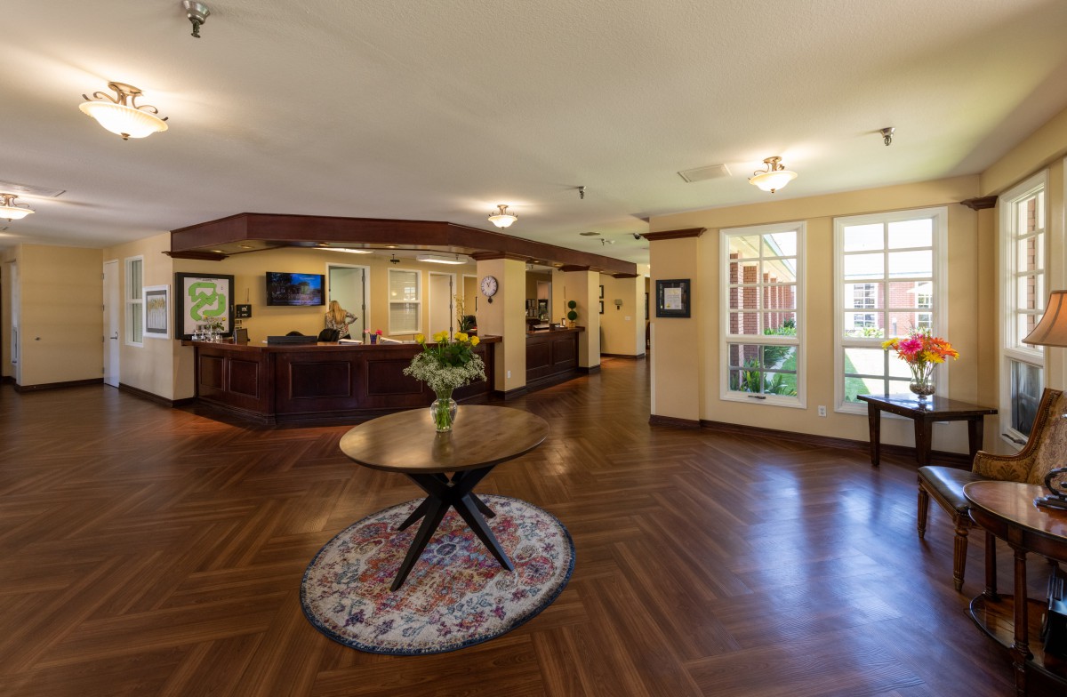 A spacious lobby with wooden flooring and a central table adorned with flowers.