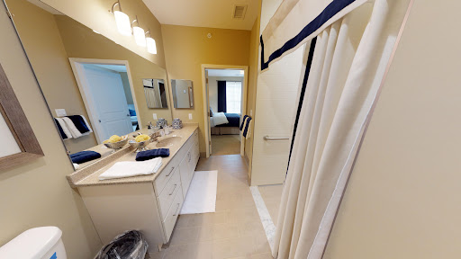 A well-lit bathroom featuring a double vanity, mirrors, and a shower area.
