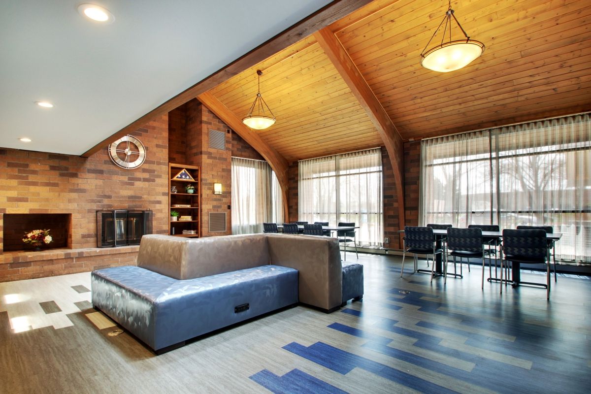 A modern living room with a wooden ceiling, featuring a fireplace and open dining area.