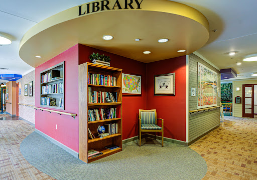 A cozy corner of a library featuring a bookshelf and comfortable seating.