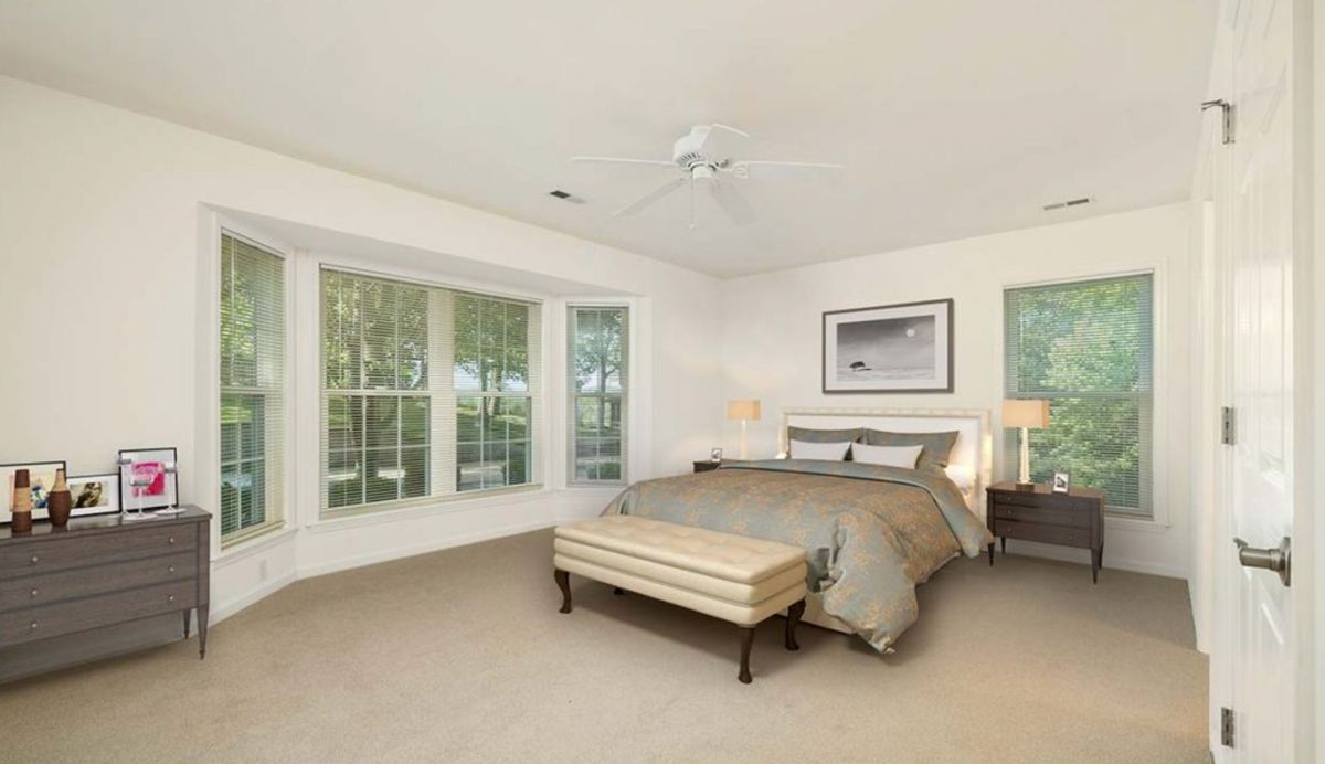 A spacious bedroom with large windows and neutral decor.