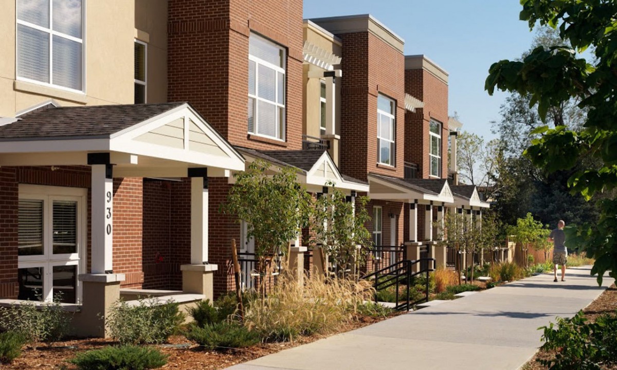 A row of modern townhouses with landscaped front yards in a suburban neighborhood.