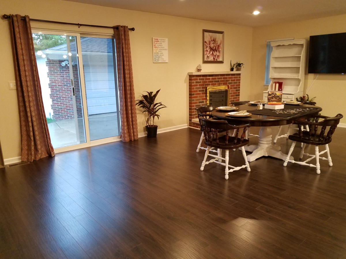 A cozy living room with a hardwood floor, featuring a dining area and fireplace.