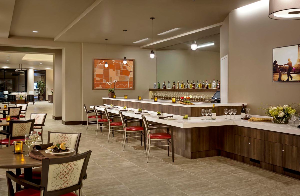 A modern restaurant interior featuring a bar with seating and contemporary artwork.