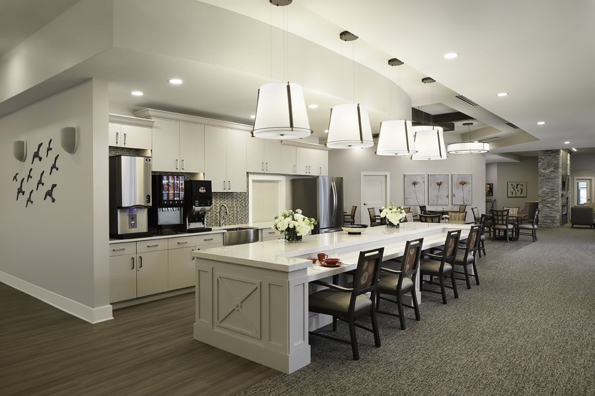 A modern kitchen with a large central island and stylish pendant lighting.