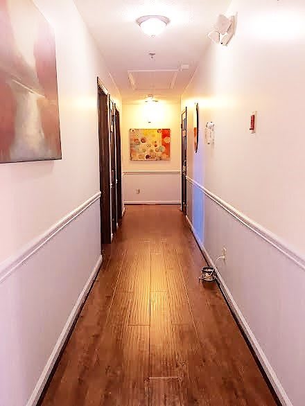 A brightly lit hallway with wooden flooring and artwork on the walls.