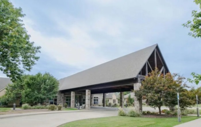 A modern building with a covered entrance and surrounding landscaping.