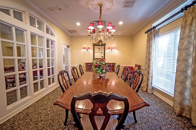 A traditional dining room featuring a large wooden table and chairs, adorned with an elegant chandelier and classic decor.