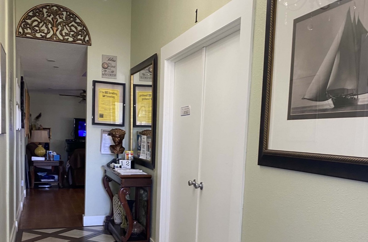 A decorated hallway featuring framed certificates and artwork, with a view of double doors and a decorative table.