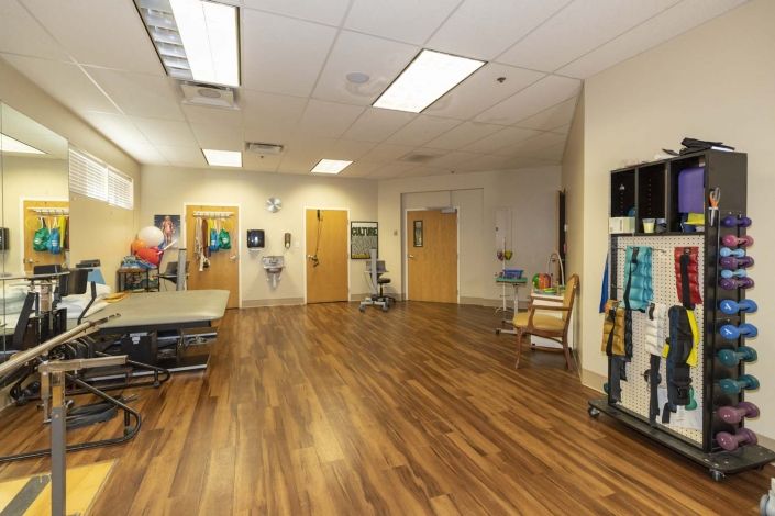 A spacious physical therapy room equipped with various exercise tools and apparatuses.