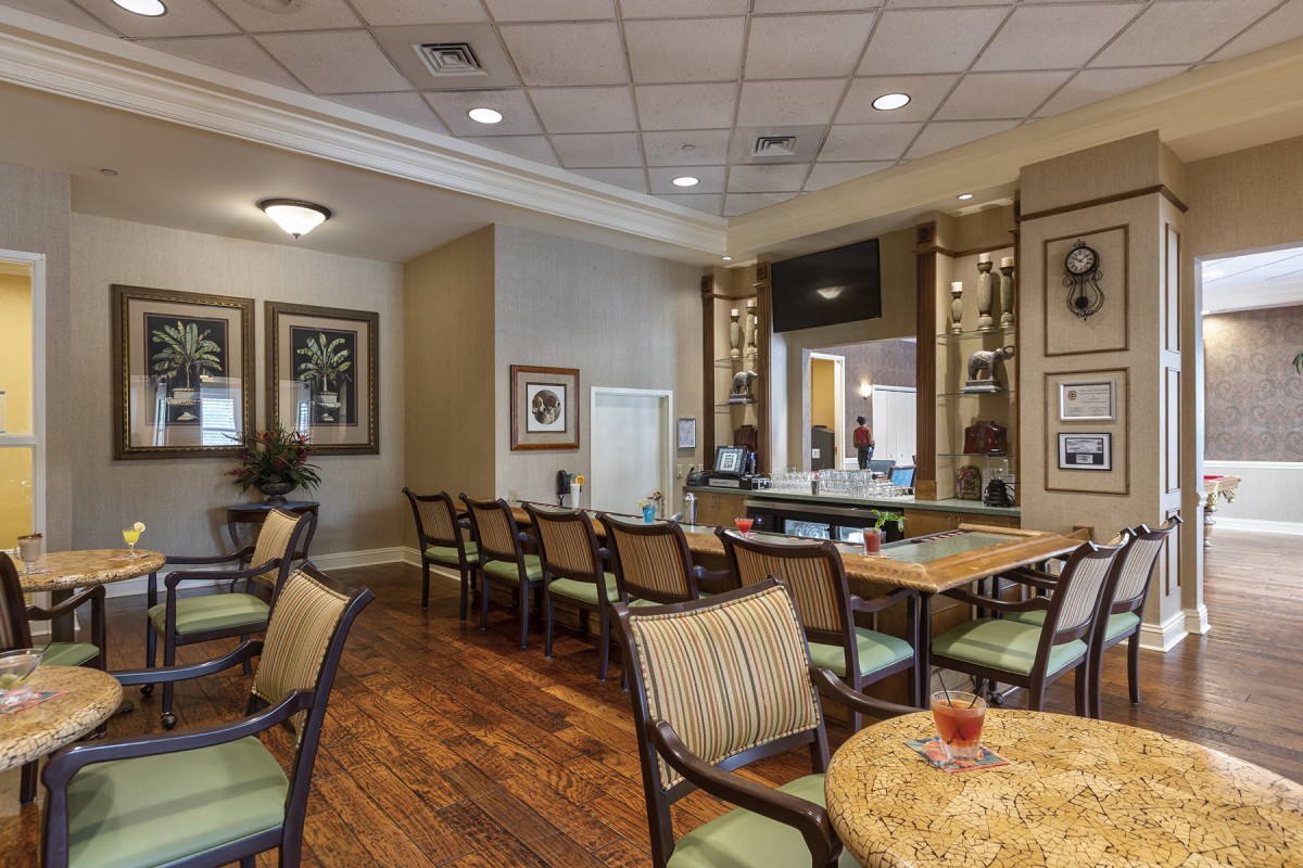 A spacious and well-decorated waiting room with chairs and tables, featuring framed artwork on the walls.