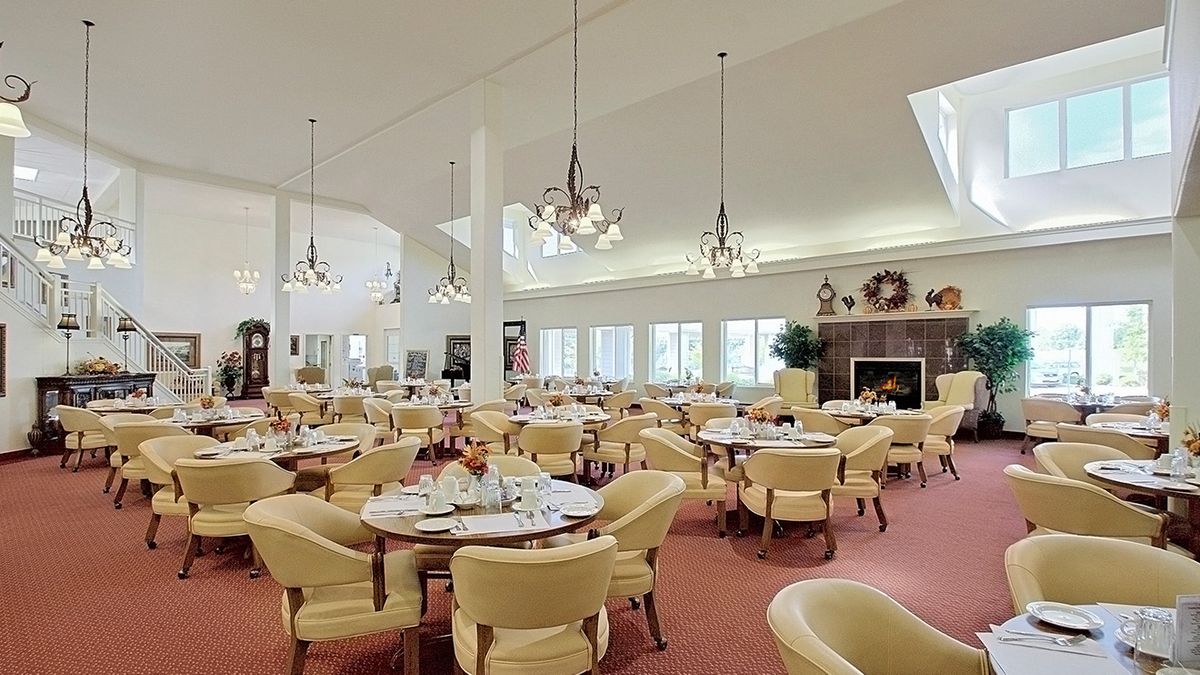 A spacious and elegant dining room with well-arranged tables and chairs, decorated with chandeliers.