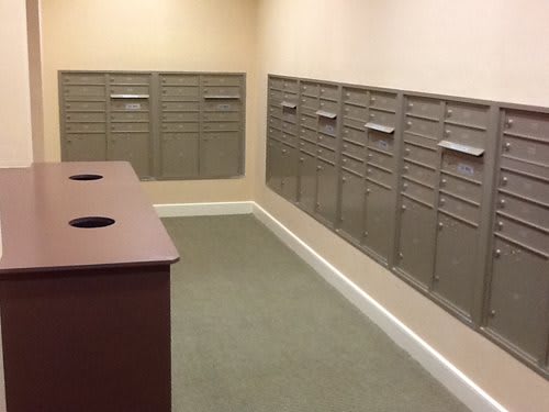 An empty mailroom with rows of metal mailboxes lining the walls.