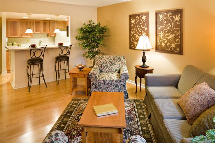 A cozy living room featuring a patterned armchair, sofa, coffee table, and decorative artwork on the wall.