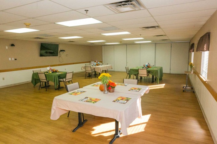 A bright, well-lit dining area with several tables and chairs arranged neatly, adorned with colorful decorations.